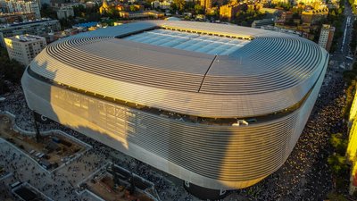 Aerial shot of Santiago Bernabéu Stadium in Madrid during sunset showcasing its modern architecture.
