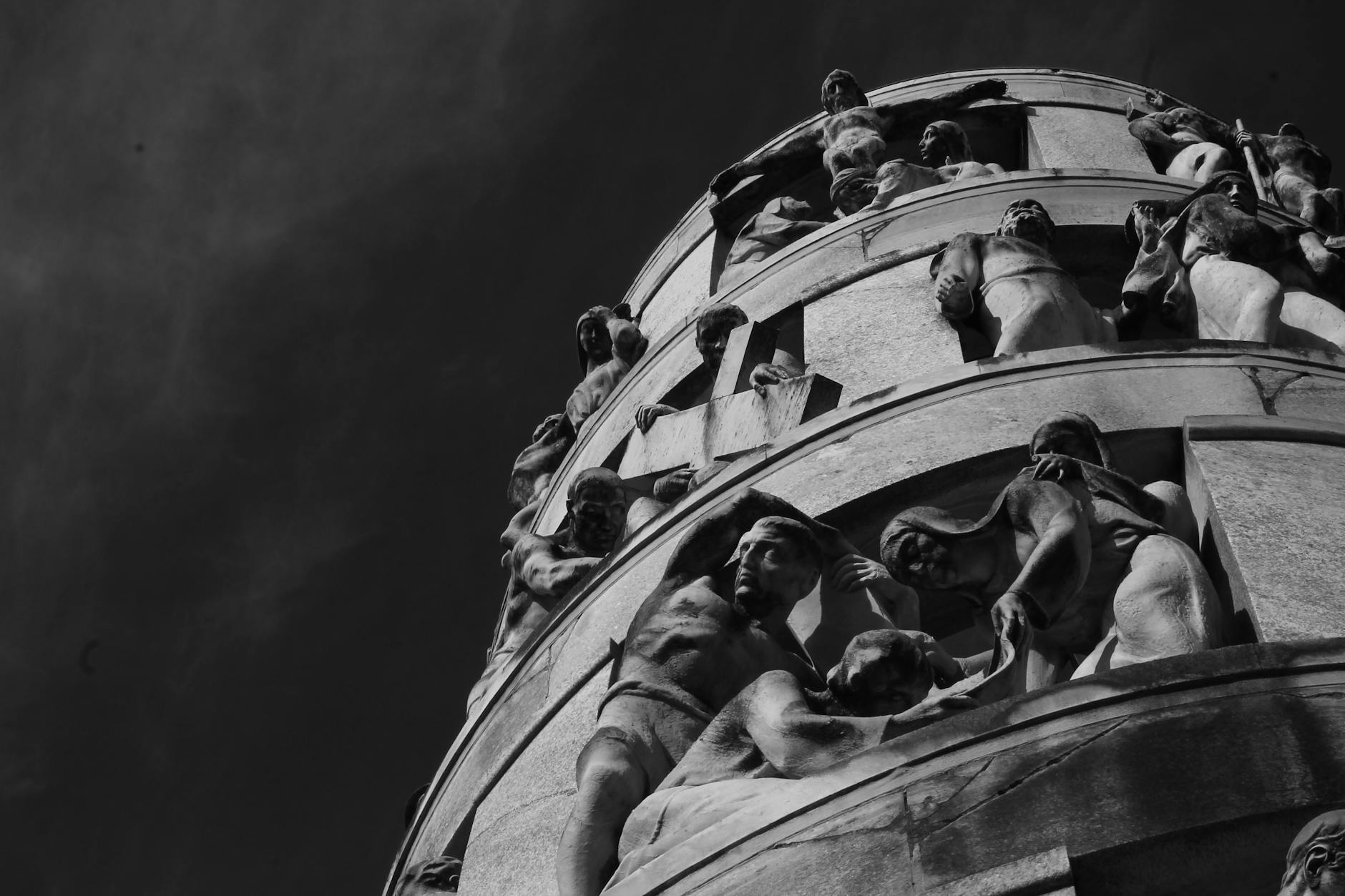 Black and white photograph capturing detailed sculptures in Milano's monumental cemetery.