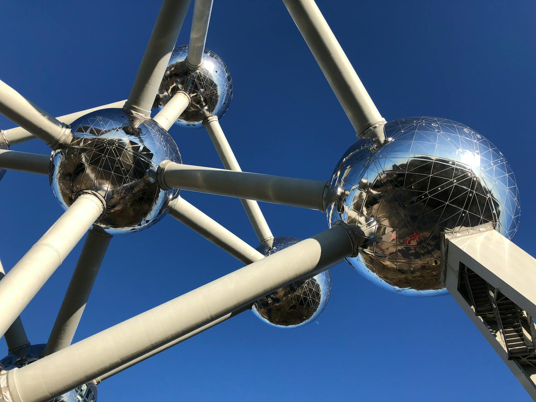 Dramatic low-angle view of the Atomium in Brussels against a clear blue sky.