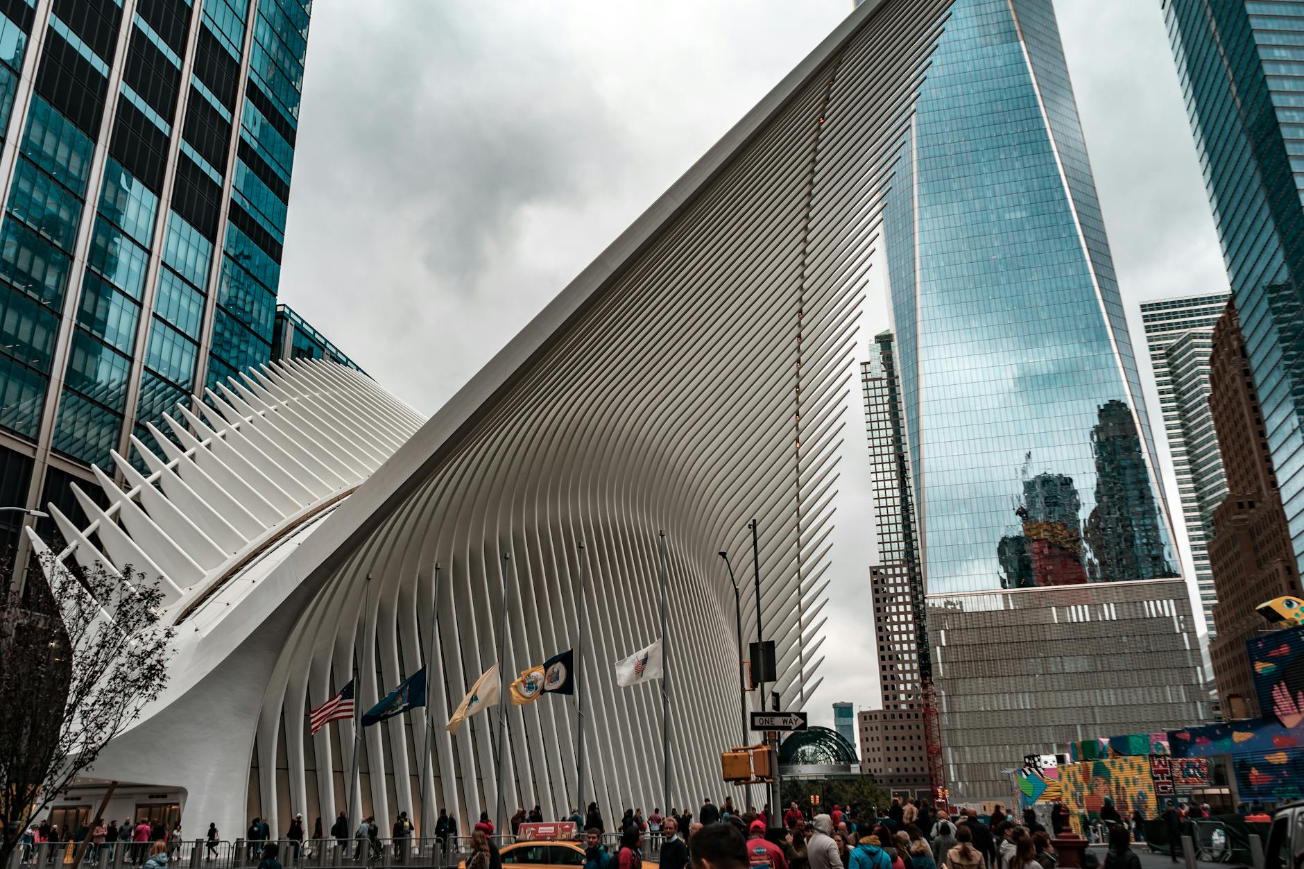 Low angle view of the Oculus outside World Trade Center in NYC, showcasing modern architecture and urban life.