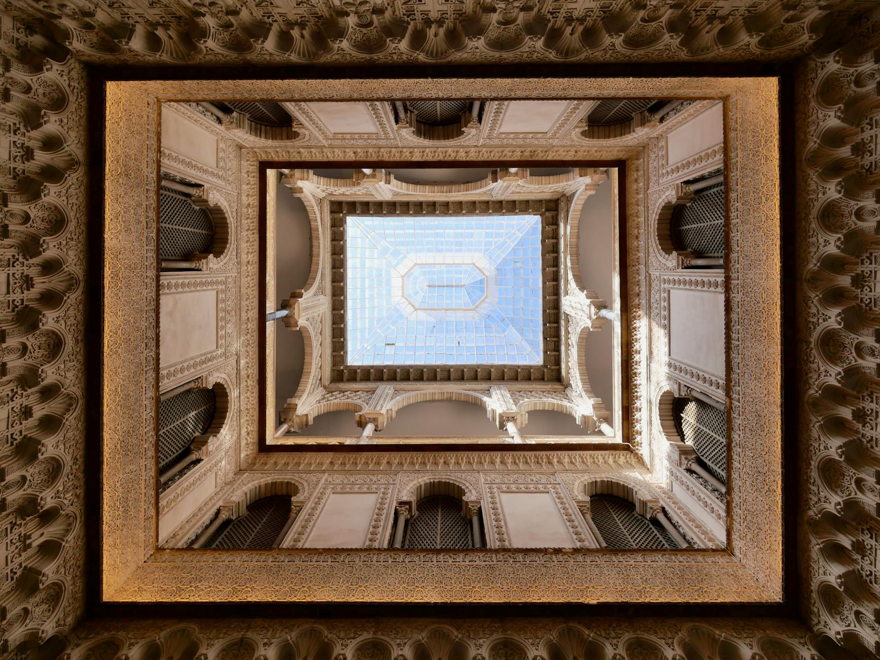 Looking up at the intricate Moorish architecture of the Alcazar in Seville, Spain.