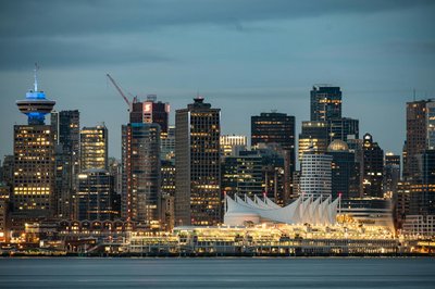 Twilight view of Vancouver skyline featuring iconic Canada Place and skyscrapers reflecting city lights.