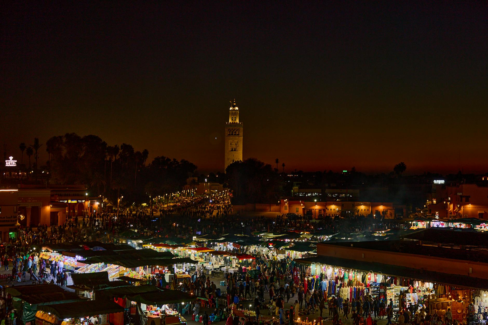 Experience the bustling night market in Marrakesh, Morocco, illuminated against a stunning twilight sky.