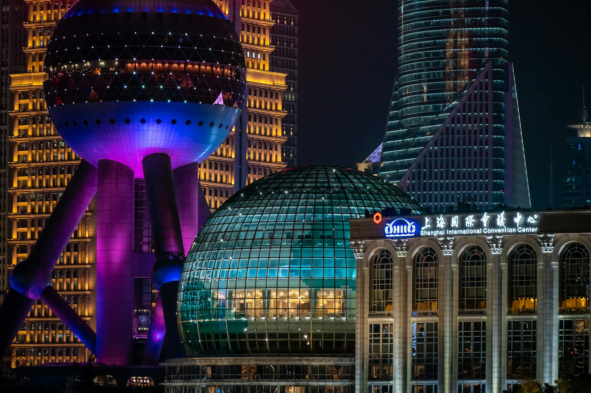Night view of the Shanghai skyline featuring the Oriental Pearl Tower and International Convention Center.