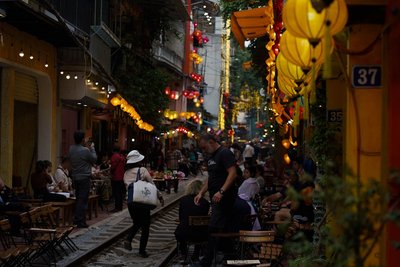a group of people walking down a street next to a train track
