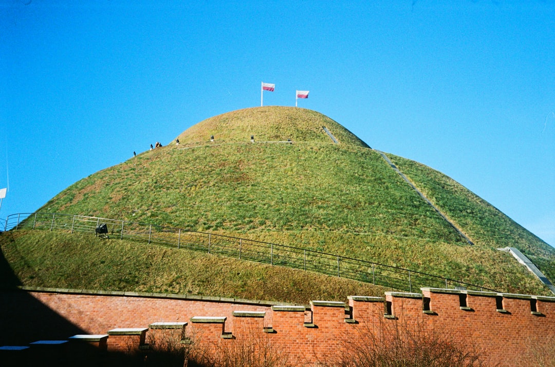 A green hill with flags in the sky.