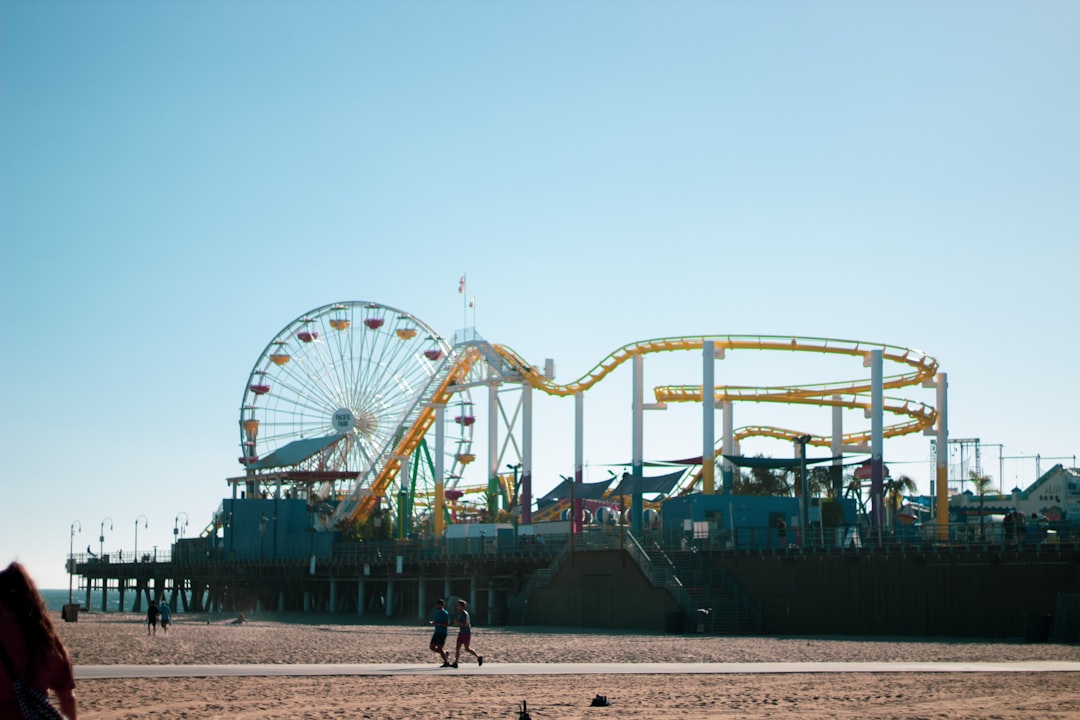 people walking on white sand near green and blue ferris wheel during daytime