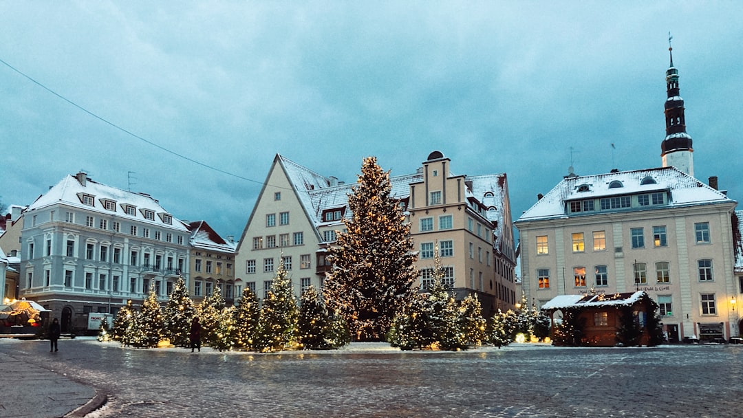 white and brown concrete building near green trees under white clouds during daytime