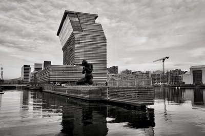 a black and white photo of a man sitting on a dock