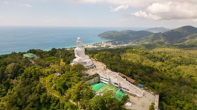 Large white buddha statue overlooking tropical island landscape