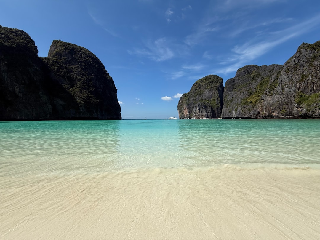 A sandy beach with a rock formation in the background