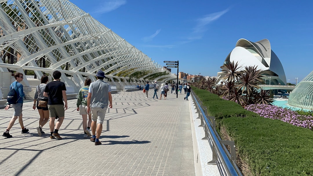 People walking along a modern architectural walkway with gardens.