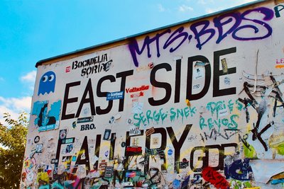 people standing near white and purple wall with graffiti during daytime