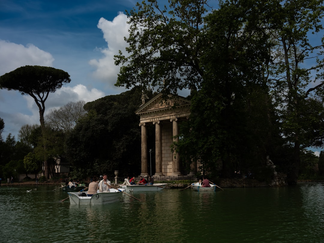 Boats float near a classical temple by the water.