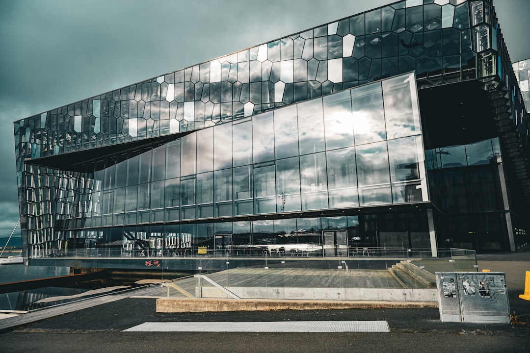 Modern building with reflective glass and a cloudy sky.