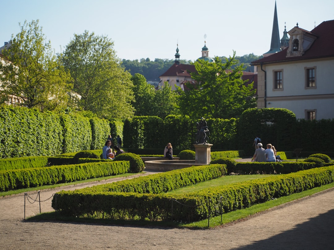 People relax in a manicured garden with a statue.