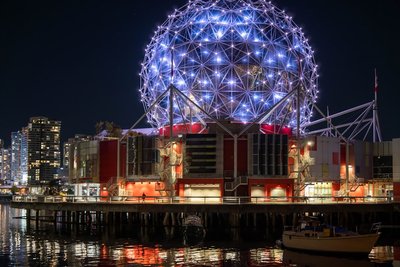 a ferris wheel lit up at night next to a body of water