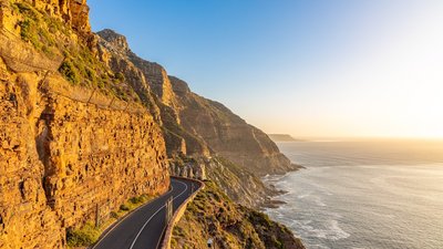 a road going down the side of a mountain next to the ocean
