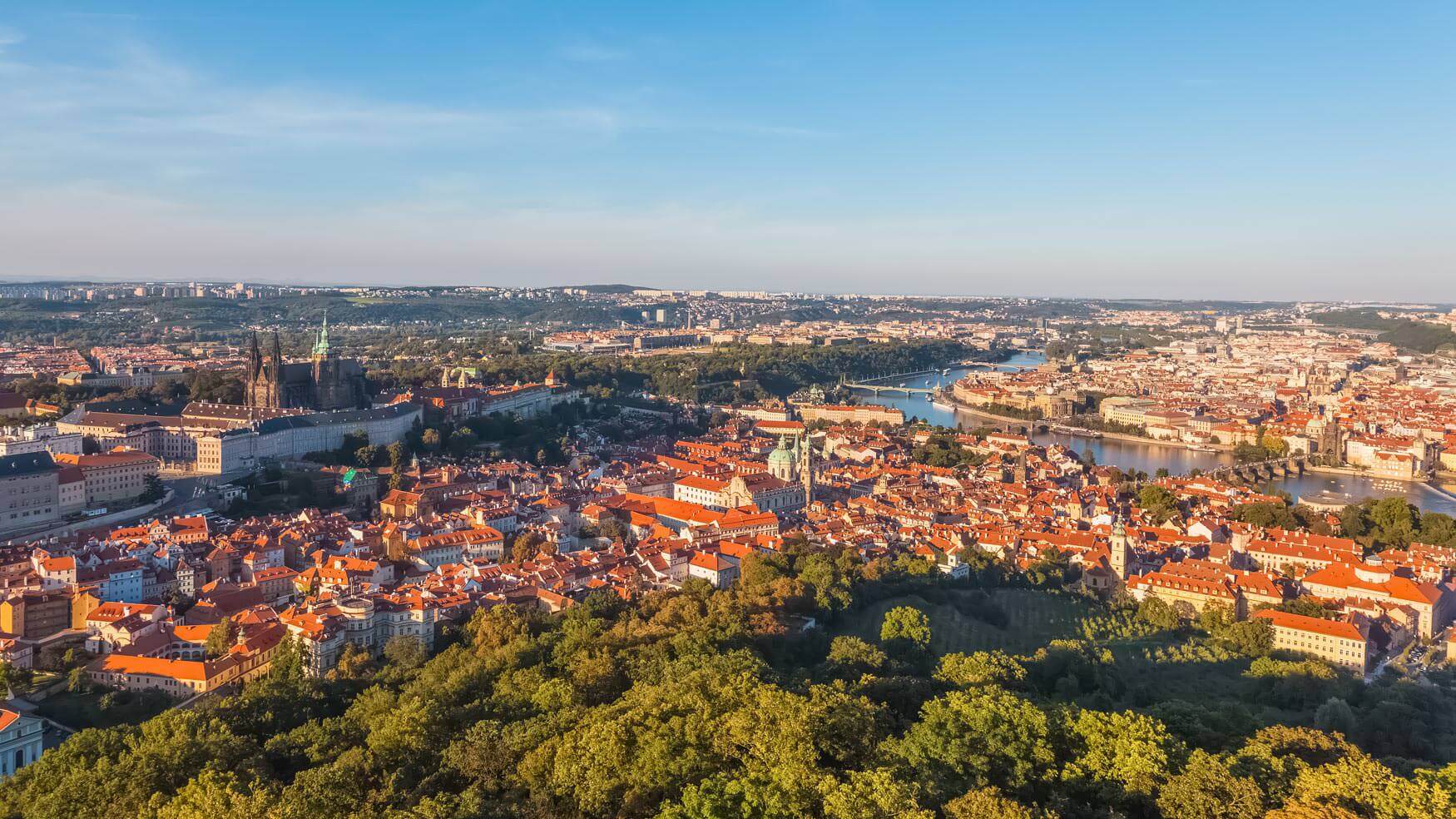 View from Petřín Tower overlooking Prague’s red rooftops, spires, and winding streets.