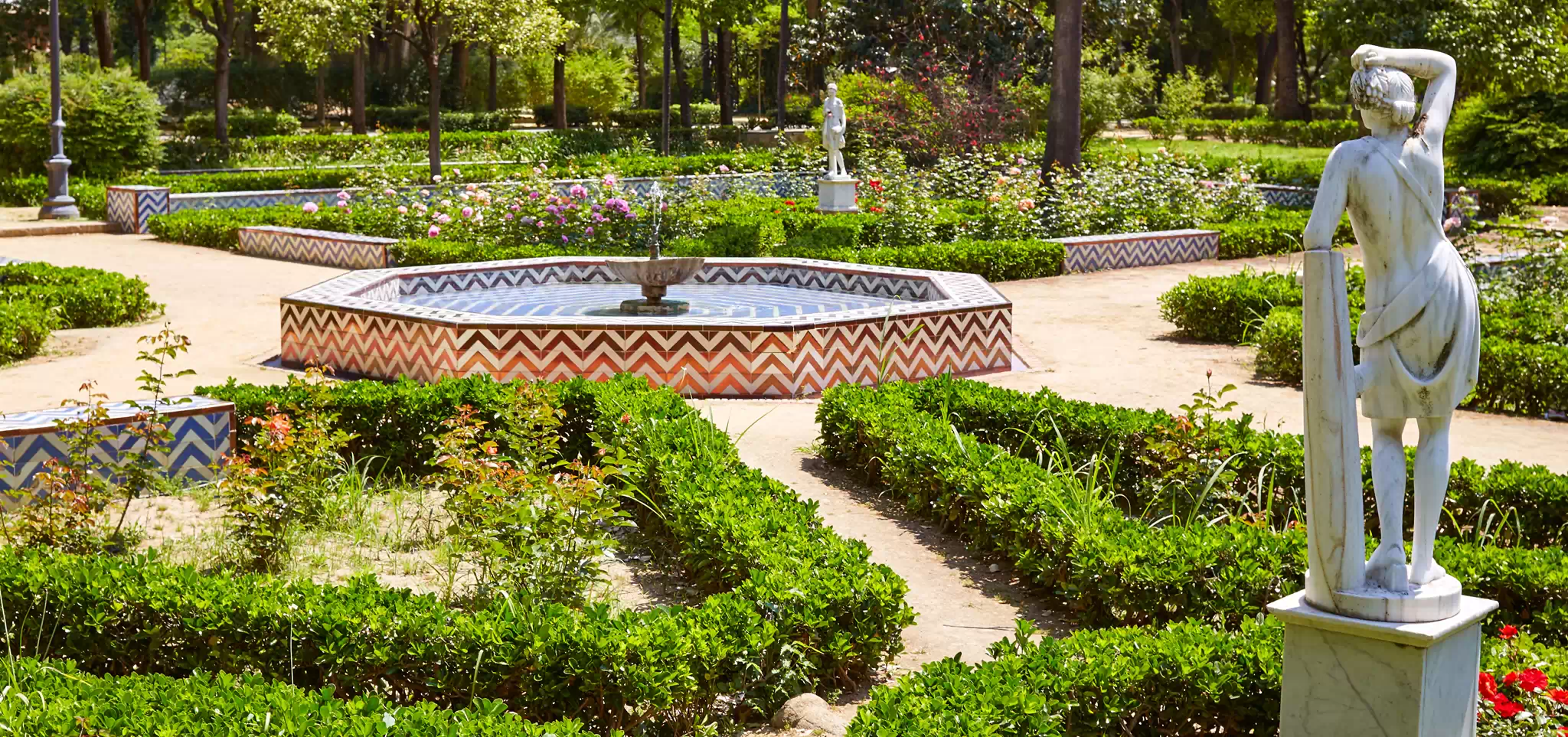 Parque de María Luisa, a beautiful green oasis in Seville with trees, flowers, and scenic walkways.
